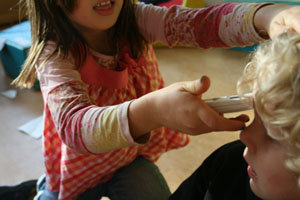 Mädchen misst mit Messgeräte die Oberflächenspannung an der Strin eines Jungen